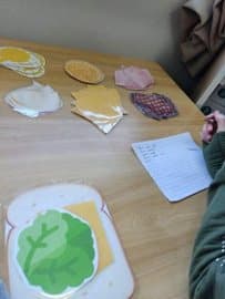 Mesa com pratos de papel e massinha verde usados para montar uma receita desplugada.