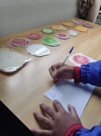 Aluno desenhando e recortando os ingredientes de uma pizza em papel.