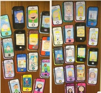 Celulares de papelão decorados com telas desenhadas, pendurados em um painel.