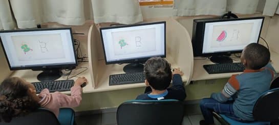 Alunos em computadores utilizando diferentes aplicativos da Cultura Digital.
