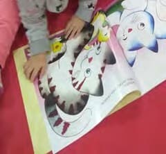 Mãos de uma criança sobre a página ilustrada de um livro, com o desenho de um gato.