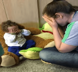 Professora e criança em atividade conjunta e compartilhada, brincando de achar e esconder.