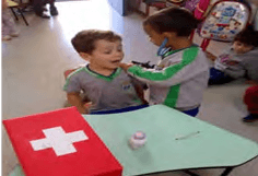 Crianças brincando de médico e paciente, assumindo papéis sociais.