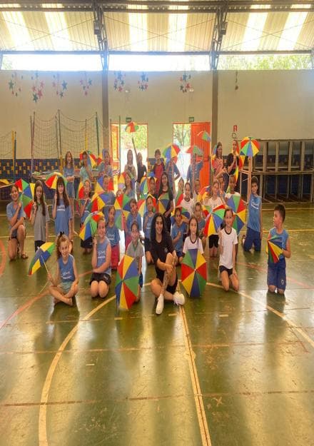 Turma posando com sombrinhas coloridas de frevo no ginásio.