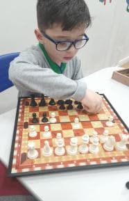Aluno jogando xadrez em um tabuleiro magnético.